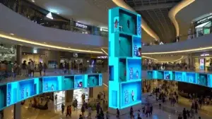 A vibrant night scene in Dhaka inspired by Times Square, featuring large digital LED billboards with colorful local advertisements, emoji graphics, fashion brands, and event promotions, surrounded by crowds and illuminated buildings—showcasing LEDADBangladesh’s dynamic outdoor advertising solutions